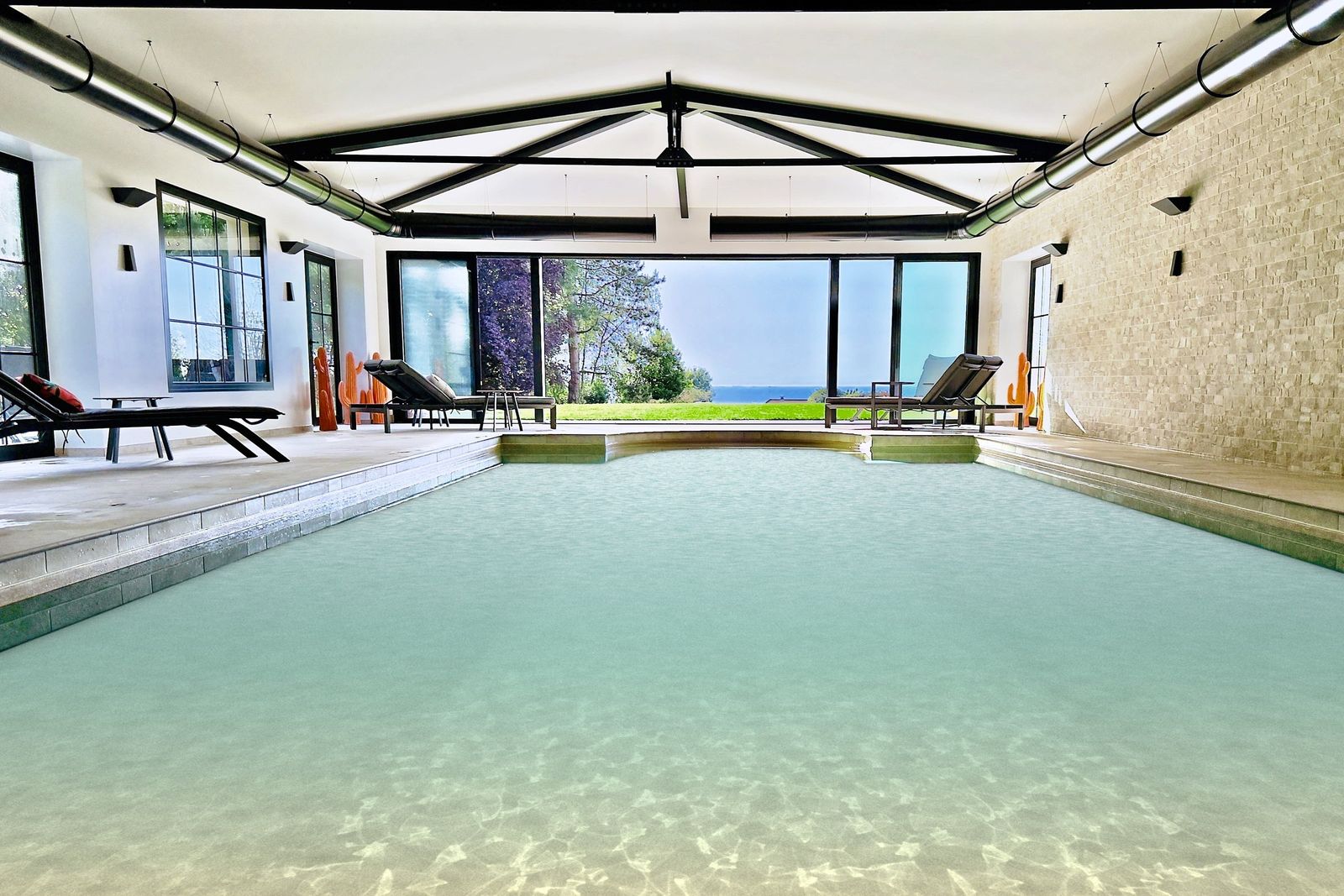 Heated indoor pool of the Holisty villa in Villerville, inside the orangery: glass doors open onto the lawn and the sea on the horizon