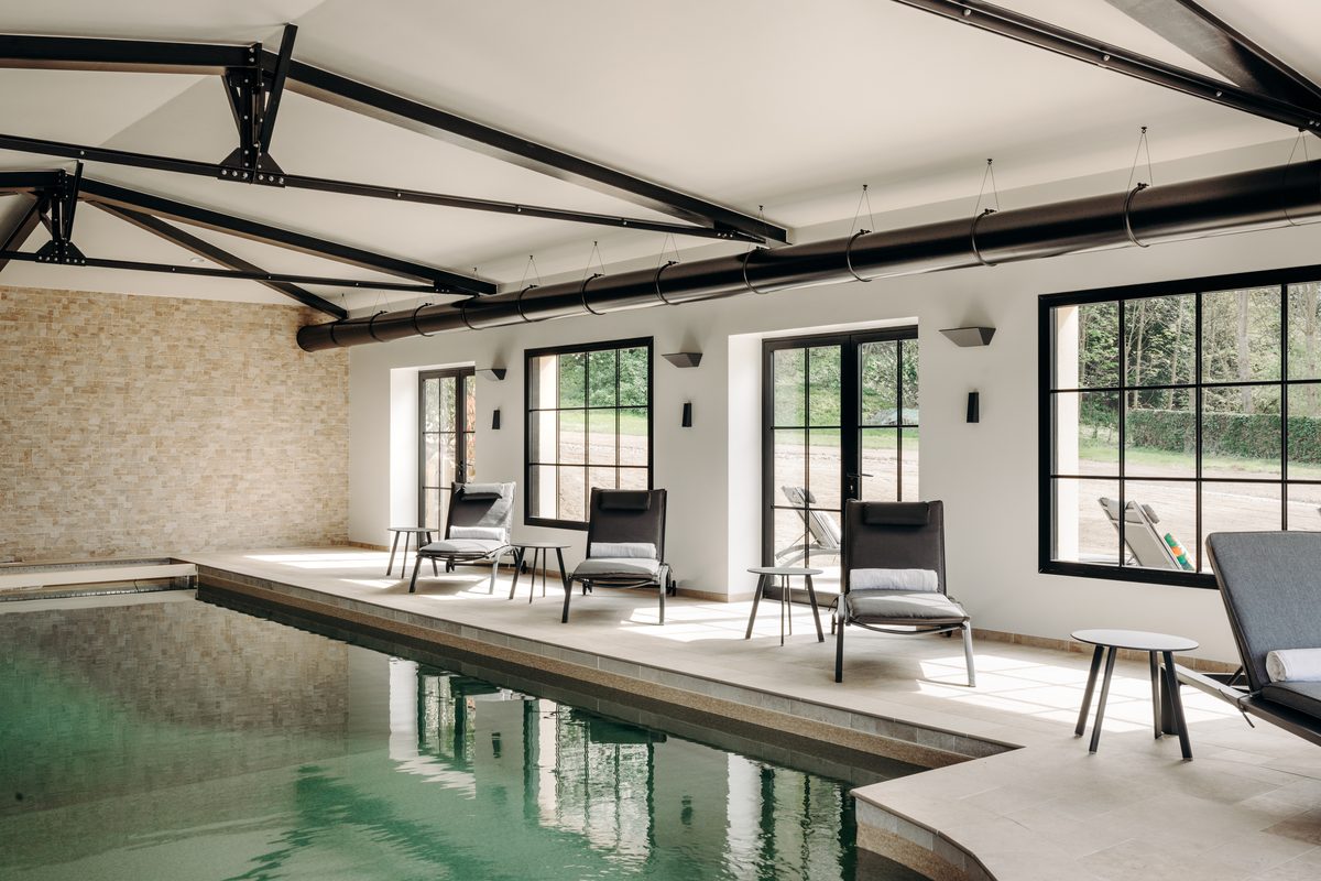 La piscine intérieure chauffée à 30 °C, vue en longueur vers les baies vitrées de l'orangerie