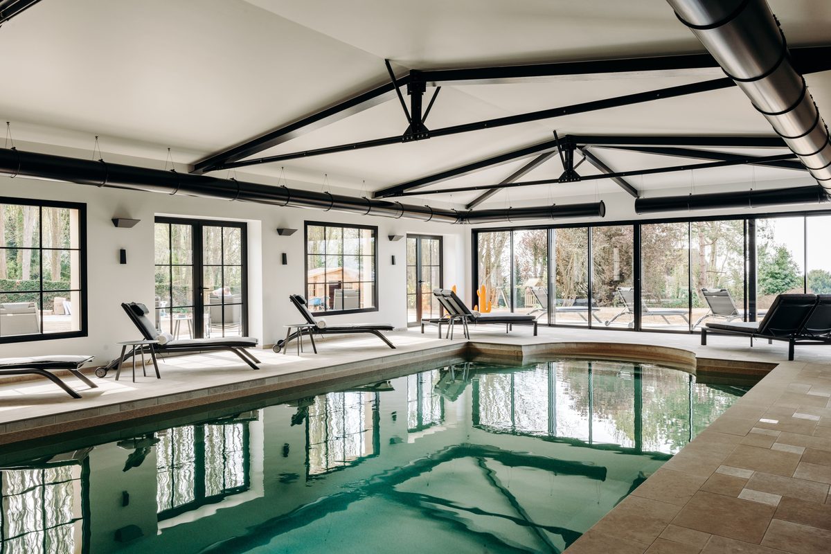The Holisty villa's heated indoor pool in the orangery, glass doors open onto the park