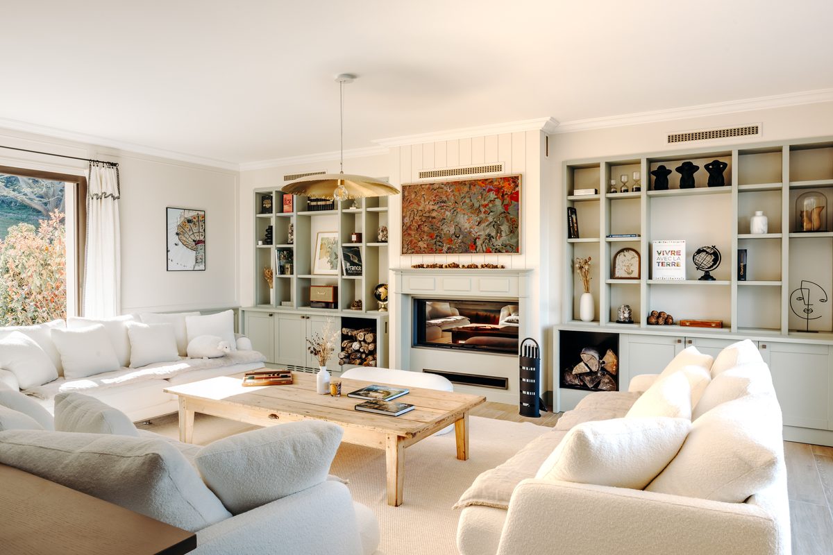 The living room sofas facing the fireplace, natural light from the tall windows