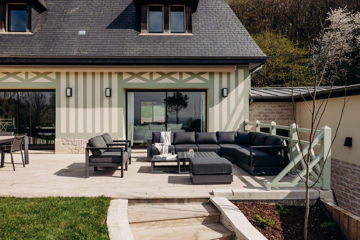 The terrace at the foot of the villa's half-timbered facade, outdoor table and armchairs